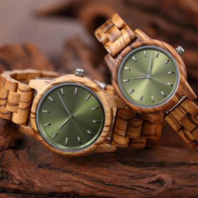 Pair of wooden watches with green faces on a wooden surface